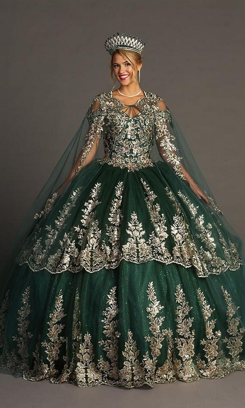 A woman wearing the Quinceanera Dress CHF3083 By Chicas, a dark green ball gown featuring gold embroidery and a matching crown, poses against a plain gray background.